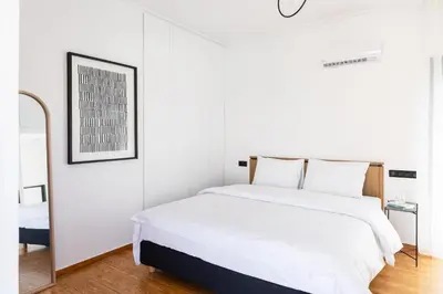 a white bedroom with a bed and a mirror at Elliot Neapoli, Athens in Athens