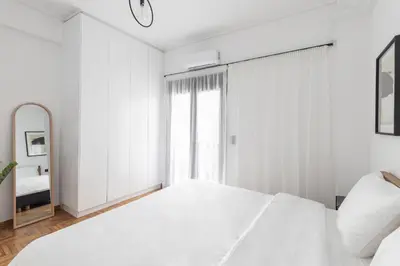 a white bedroom with a large bed and a mirror at Elliot Neapoli, Athens in Athens