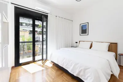 a white bedroom with a large bed and a large window at Elliot Neapoli, Athens in Athens