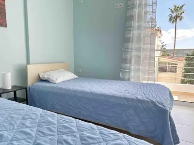a bedroom with two beds and a window with a palm tree at Riviera beach, seaside spacious apt. in Anavissos