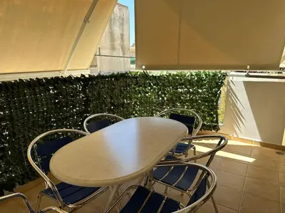 a table and chairs in front of a green hedge at Riviera beach, seaside spacious apt. in Anavissos