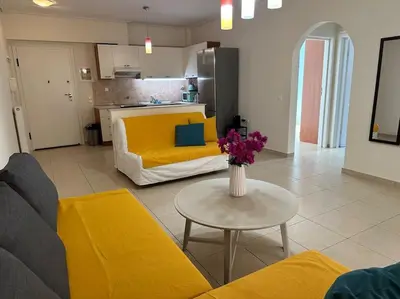a living room with a yellow couch and a table at Riviera beach, seaside spacious apt. in Anavissos
