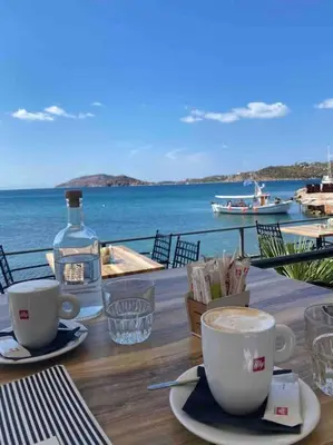 a table with two cups of coffee and a bottle of water at Riviera beach, seaside spacious apt. in Anavissos