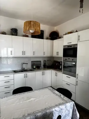 a kitchen with white cabinets and a table and a sink at Attica Vacation Home in Dhaskalión