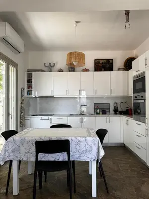 a kitchen with white cabinets and a table and chairs at Attica Vacation Home in Dhaskalión