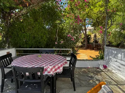 a table and chairs on a patio with pink flowers at Attica Vacation Home in Dhaskalión