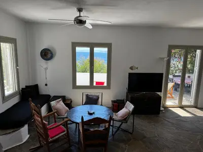 a living room with a table and chairs and a tv at Attica Vacation Home in Dhaskalión