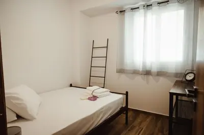 a bedroom with a bed with white sheets and a window at Aria apartment in Athens