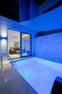 a large bath tub in a room with blue lights at White Cliff Luxury Suites in Porto Rafti