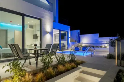 a patio with a table and chairs and a pool at White Cliff Luxury Suites in Porto Rafti