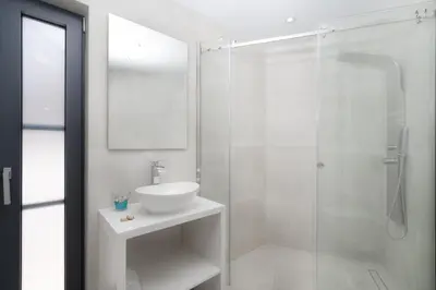 a white bathroom with a sink and a shower at White Cliff Luxury Suites in Porto Rafti