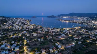 an aerial view of a city and a harbor at night at White Cliff Luxury Suites in Porto Rafti