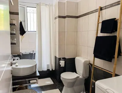 a bathroom with a white toilet and a sink at My Porto Villa in Porto Rafti