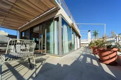a white chair on a patio with a building at Superior Penthouse in Athens Riviera in Athens