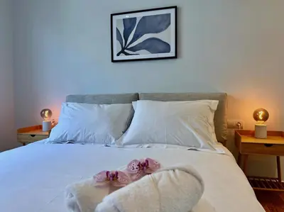 a bedroom with a bed with white sheets and two lamps at AgiasFoteinis20 in Athens