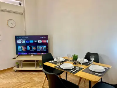 a dining room with a table with chairs and a tv at New City Apartment Neos Kosmos in Athens