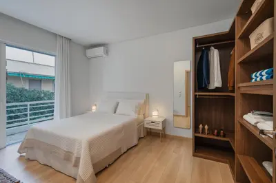 a bedroom with a white bed and a large window at Athens Sea Front Apartment, Varkiza in Varkiza