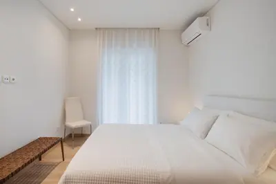 a white bedroom with a white bed and a window at Athens Sea Front Apartment, Varkiza in Varkiza