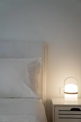 a bed with a white pillow and a lamp on a night stand at Athens Sea Front Apartment, Varkiza in Varkiza