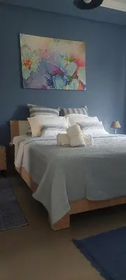 a bedroom with a white bed with a painting on the wall at Velvet new apt in Ilissia in Athens
