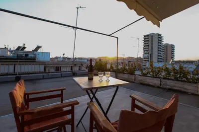 a table with a bottle of wine and chairs on a roof at Loft condo next to metro station. Amazing view! in Athens