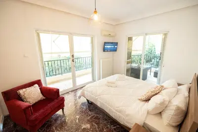 a bedroom with a white bed and a red chair at Love Travel Athens Apartments in Athens