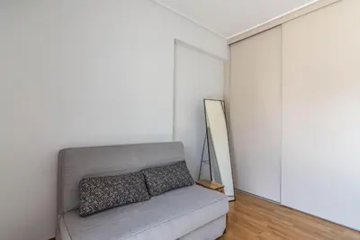 a living room with a gray couch and a white wall at Light in Athens