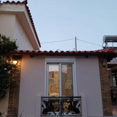 a white house with a balcony with a window at Boutique Eptalofos 15min from airport and sea in Kouvarás