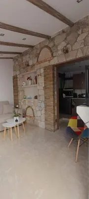 a living room with a stone wall with a table and chairs at Boutique Eptalofos 15min from airport and sea in Kouvarás