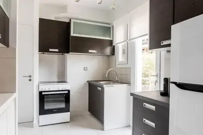 a kitchen with black and white cabinets and appliances at Breezy 2BR Apartment by Marina Flisvos by UPSTREET in Athens