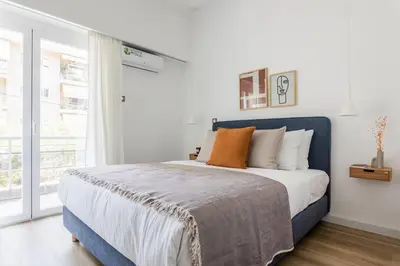 a bedroom with a blue and white bed and a window at Breezy 2BR Apartment by Marina Flisvos by UPSTREET in Athens