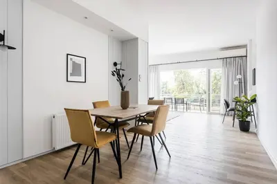 a white dining room with a wooden table and chairs at Breezy 2BR Apartment by Marina Flisvos by UPSTREET in Athens