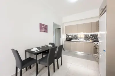 a kitchen and dining room with a black table and chairs at New Spacious & Stylist Apt in Piraeus