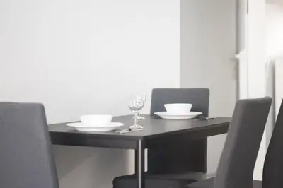 a dining table with a glass of wine and chairs at New Spacious & Stylist Apt in Piraeus
