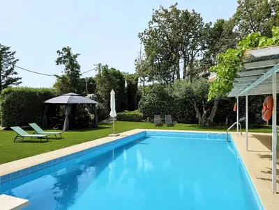 a swimming pool in a yard with an umbrella at Lagonisi Beach House in Lagonissi