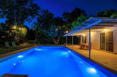 a swimming pool in front of a house at night at Lagonisi Beach House in Lagonissi