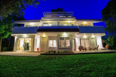 a large white house with a lawn in front of it at Lagonisi Beach House in Lagonissi