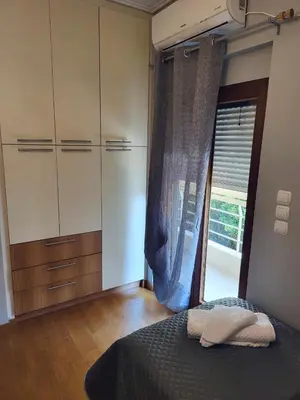 a bedroom with a bed and cabinets and a window at Luxe Apartment in Central Glyfada in Athens