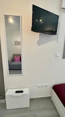 a mirror on a wall with a couch in a room at Harihara Guesthouse near Airport in Paianía