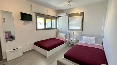 a hotel room with two beds and a tv at Harihara Guesthouse near Airport in Paianía