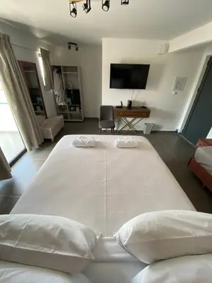 a large white bed in a room with a tv at Airport Luxury Stay in Artemida
