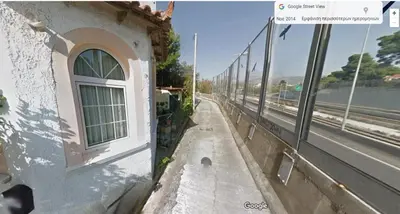 a building with a window next to a road at Metro Paĺlini Rooms to Rent 20 min to Syntagma 15 minutes to Airport 24 hours train Bus and 200 meter aŵay in Pallíni