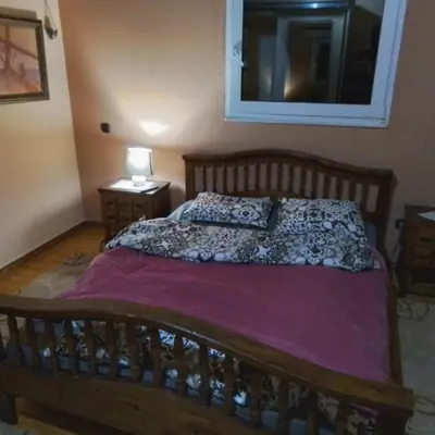 a bedroom with a bed with a wooden frame at Metro Paĺlini Rooms to Rent 20 min to Syntagma 15 minutes to Airport 24 hours train Bus and 200 meter aŵay in Pallíni