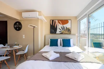 a bedroom with a large bed and a table and chairs at Aiolos new Smyrni view loft suite in Athens