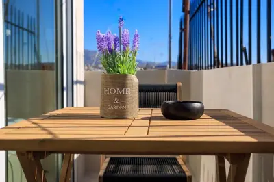 a wooden table with a vase with purple flowers on it at Aiolos new Smyrni view loft suite in Athens