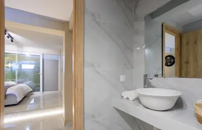 a white bathroom with a sink and a bedroom at Aiolos new Smyrni view loft suite in Athens
