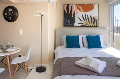 a bedroom with a bed and a table and a clock at Aiolos new Smyrni view loft suite in Athens