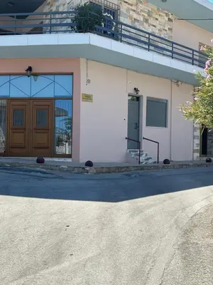 a building with a wooden door and a balcony at Paola’s Apartment Near Athens Airport in Spáta