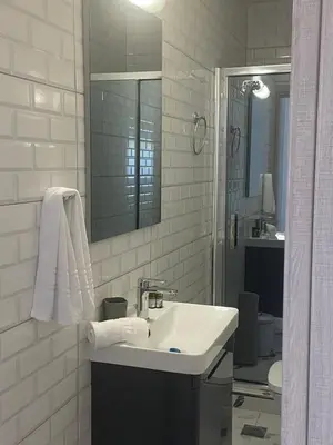 a white bathroom with a sink and a mirror at Paola’s Apartment Near Athens Airport in Spáta