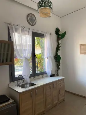 a kitchen with a sink and a window with curtains at Paola’s Apartment Near Athens Airport in Spáta
